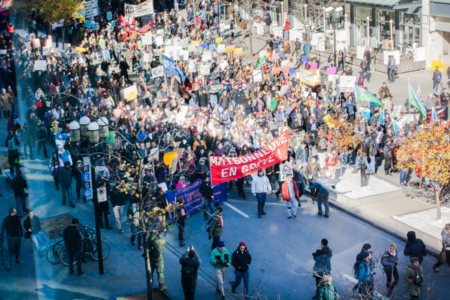 A photo showing a street full of people holding a red banner saying "Maisonneuve en greve."